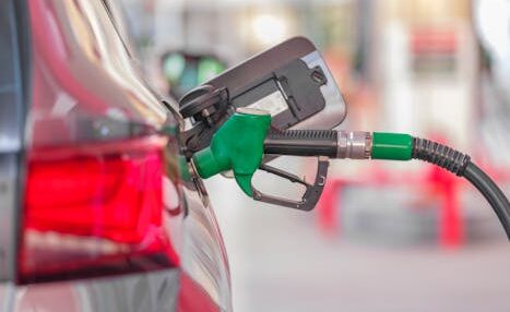 A close-up view of a fuel pump nozzle inserted into a car's tank at a gas station.
